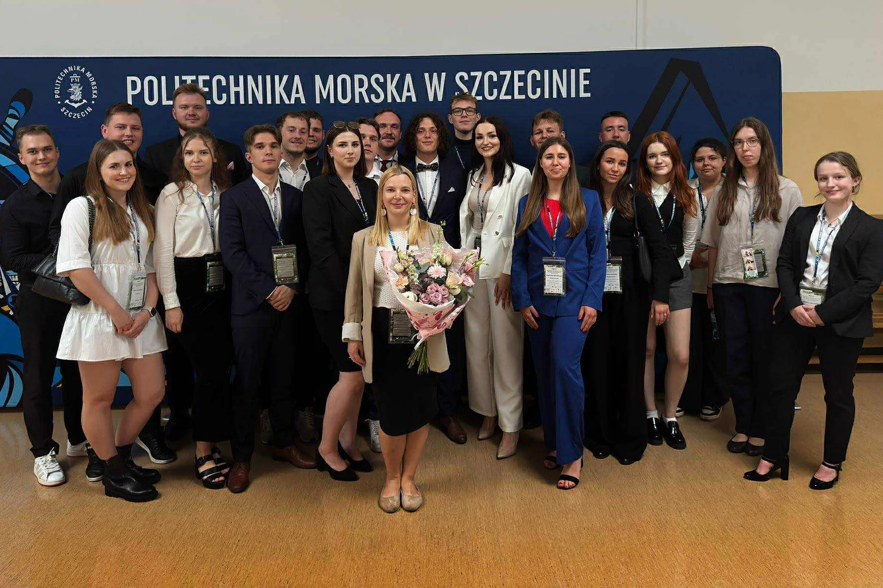 Członkowie Koła Naukowego Logistyki i Transportu PM na tle ścianki Pm